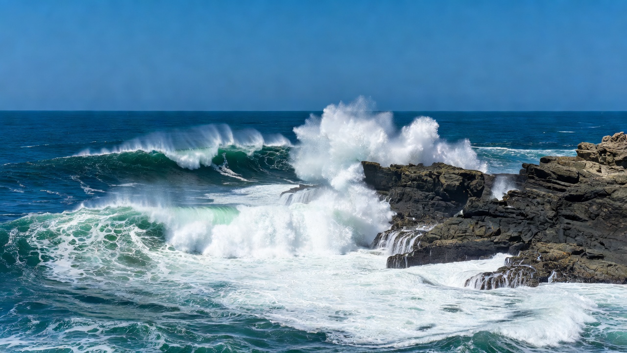 Ocean waves breaking near a rocky headland on a clear day